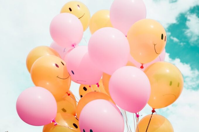 Gula och rosa ballonger fyllda med helium mot en blå himmel.