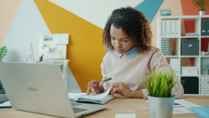 Person granskar anteckningar vid laptop och går igenom material