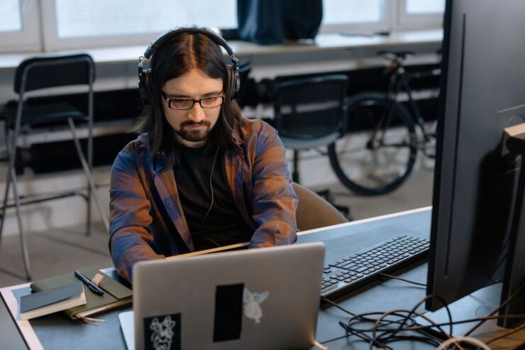 Person med hörlurar arbetar vid laptop och extern skärm