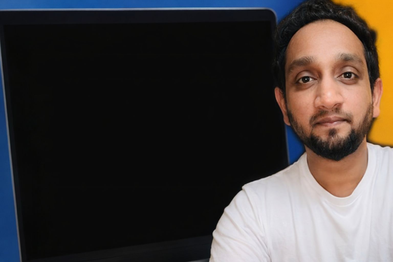 En man tittar in i kameran med en svart skärm i bakgrunden.